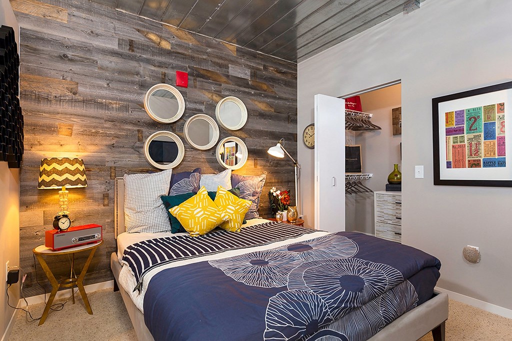 a bedroom with a bed with blue and yellow pillows and a reclaimed wood wall a bedroom with a bed with blue and yellow pillows and a reclaimed wood wall at Ann Arbor City Club, Ann Arbor Michigan